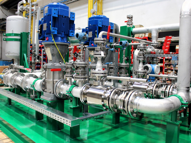 Detailed view of an Apollo cooling water system with green base frame, stainless steel piping, and two vertical pumps.