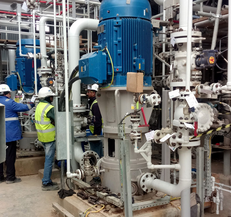 In einer industriellen Umgebung in einem Chemiewerk ist eine vertikale, mehrstufige VS6 Prozesspumpe vom Apollo Typ HPTV installiert. Neben der Pumpe steht ein Arbeiter in Sicherheitskleidung und kontrolliert die Anlagenwerte.