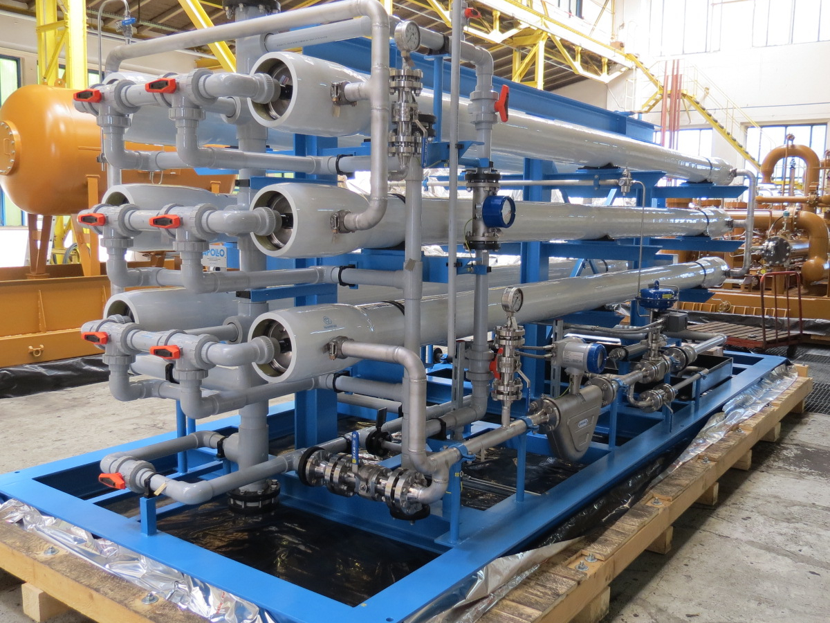 The image shows a detailed view of a sulfate removal skid standing on a wooden packaging base in the Apollo hall.