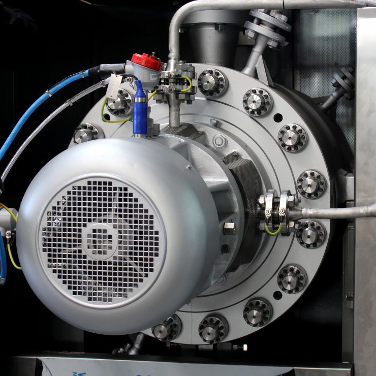 Nahaufnahme auf eine Prozesspumpe welche in eine Schallhaube installiert ist. Blick fällt auf metallische glänzenden Abdeckung der Lagerung, massiven Barrel mit Schrauben und Anschlussverrohrung.