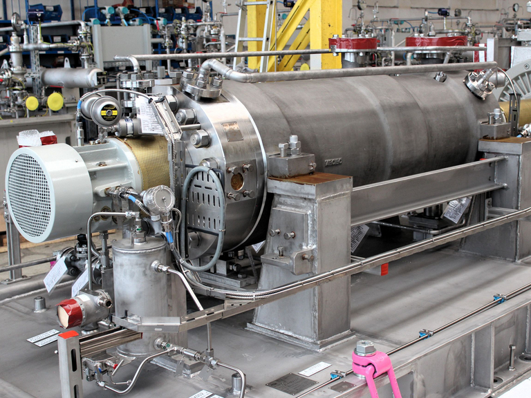 seitliche frontale Nahaufnahme einer back-to-back-Barrelpumpe des Apollo Types TGD mit Verrohrung zu Schmierölsystem und im Hintergruind ist der Elektromotor zu sehen.