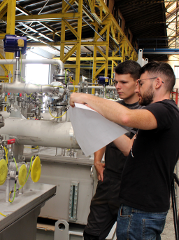 Mitarbeiter in der Fertigung begutachten Komponenten eines Schmierölsystems für den Anlagenbau.