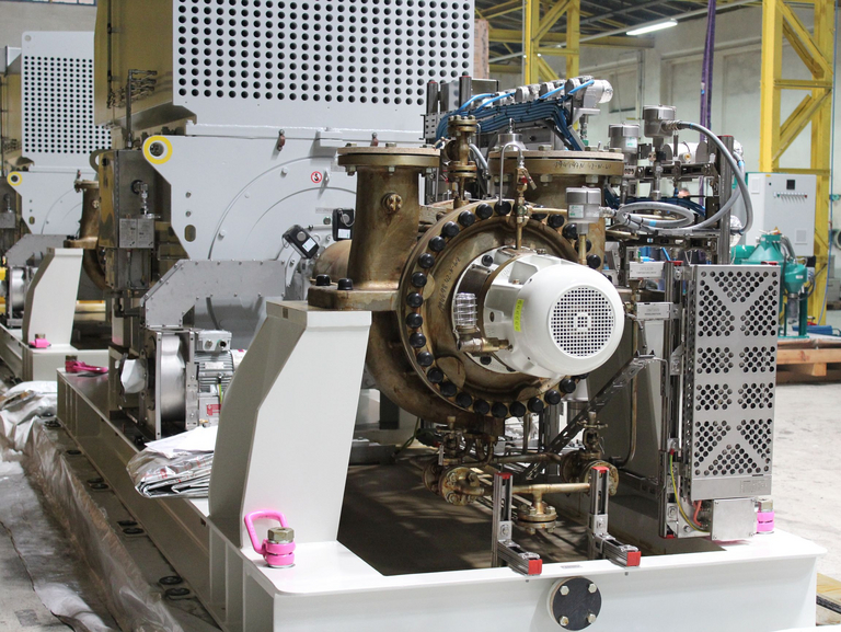 Frontaler Blick auf eine API 610, BB2 Pumpe, montiert auf einem weißen Grundrahmen mit einem seitlich angebrachten Schmierölsystem und dahinter ein grau lackierter Elektromotor.