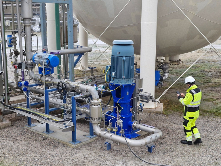 Vertikale Topfpumpe vom Typ Apollo GLKV (API 610, VS6), installiert in einer industriellen Düngemittelanlage; ein Techniker in vollständiger persönlicher Schutzausrüstung (PSA) steht neben der Anlage und verdeutlicht die Dimensionen der Pumpe.